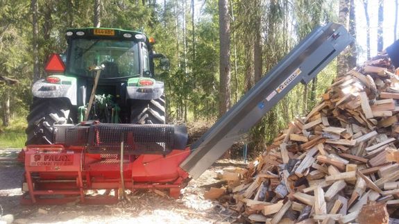 Traktoriin liitetty klapikone pilkkomassa puita